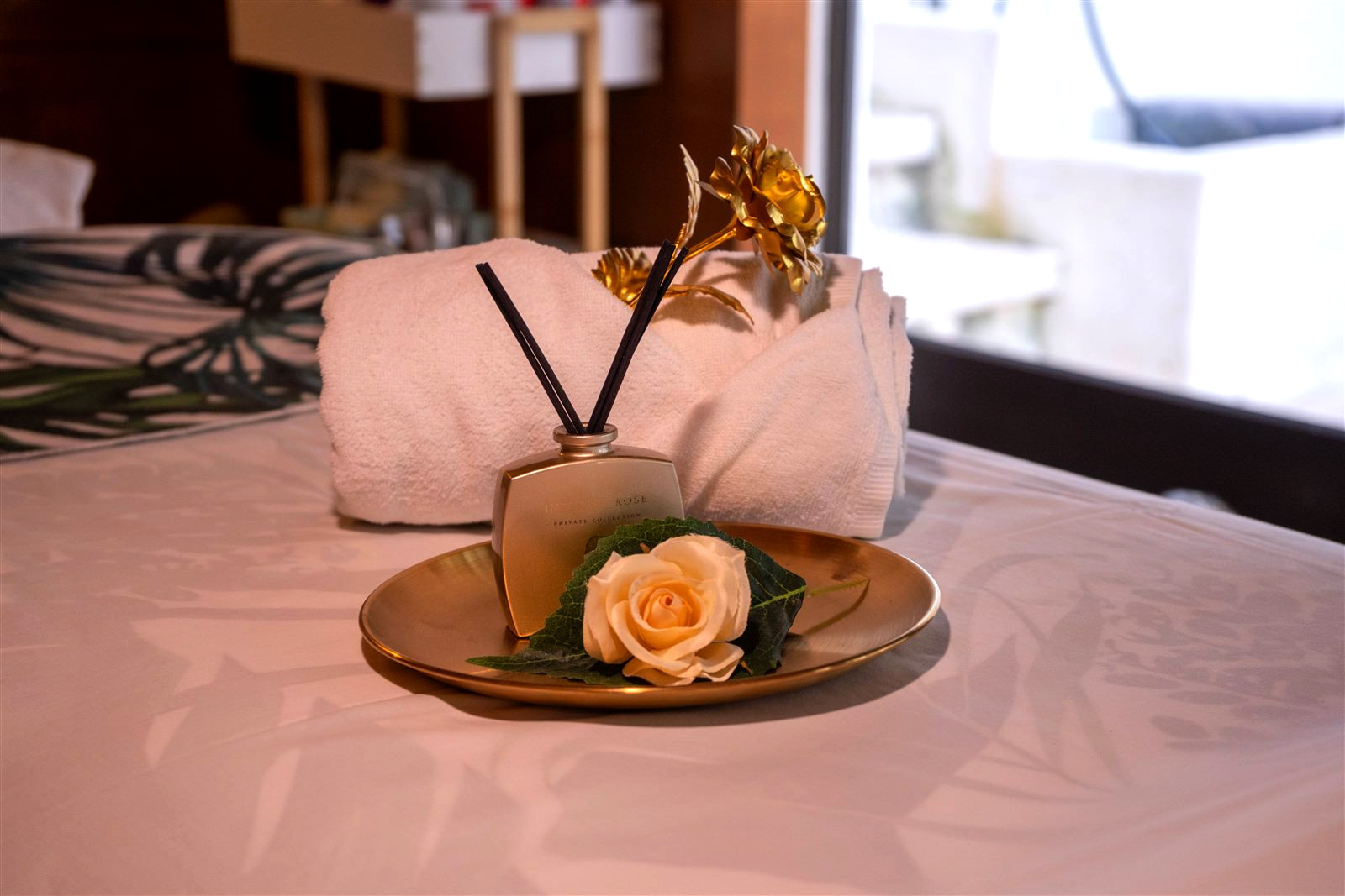 Sala de massagem da clínica preparada com toalha, difusor e rosa